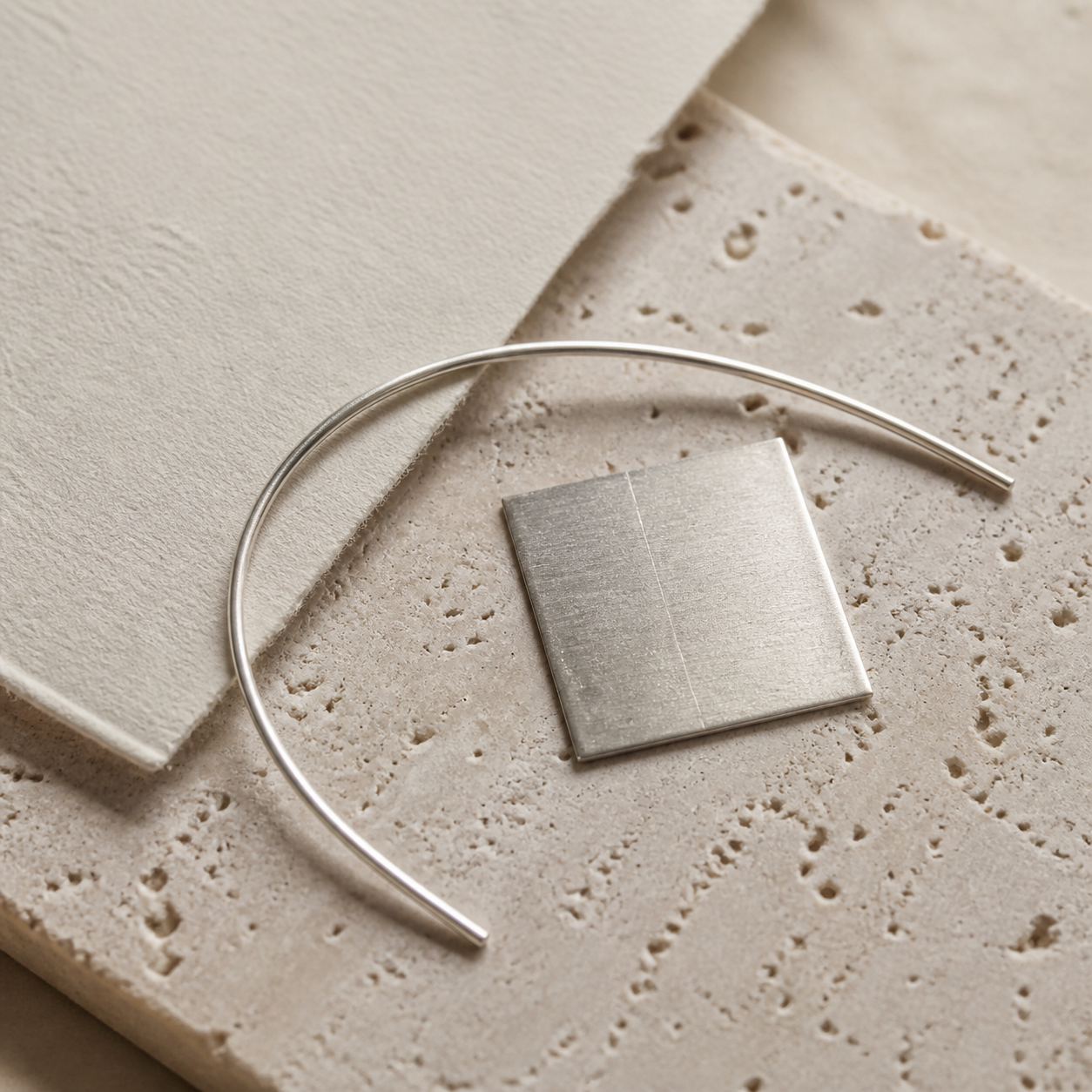 Silver-tone wire and a brushed metal sample on pale limestone, shown as a material illustration