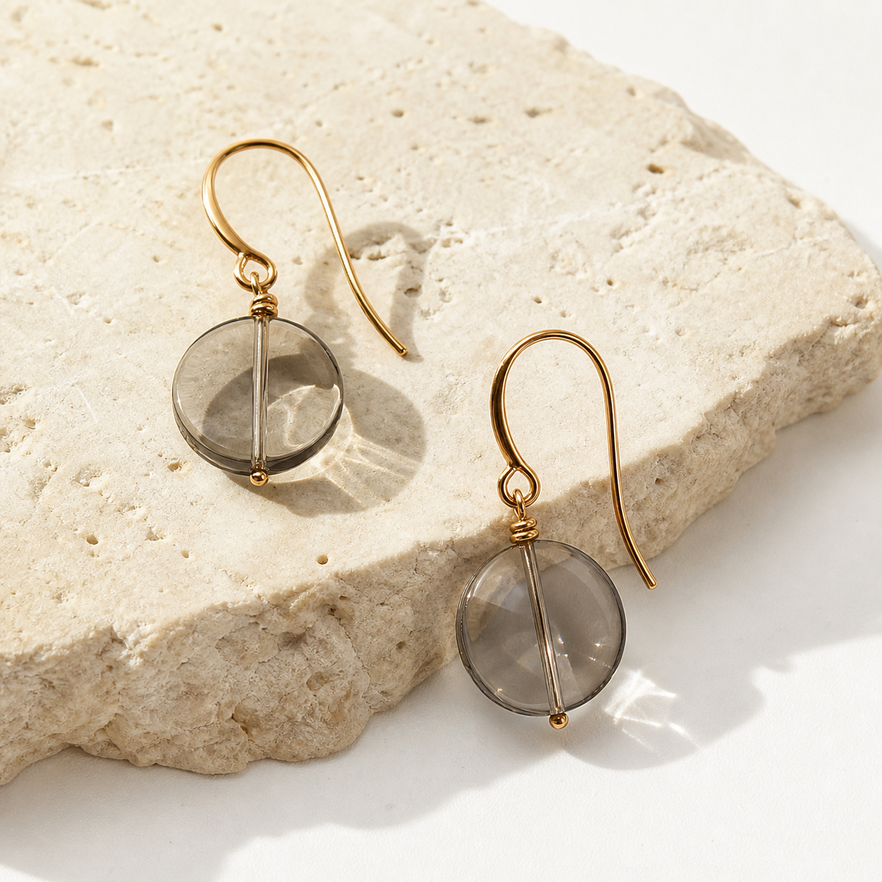 Pair of translucent smoky-grey round drop earrings with gold-tone hooks